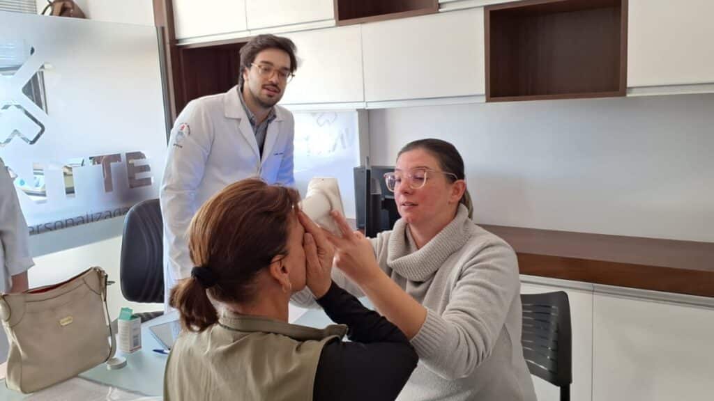 Imagem mostra dois médicos fazendo exames em uma pessoa com diabetes para possível diagnóstico de retinopatia diabética.