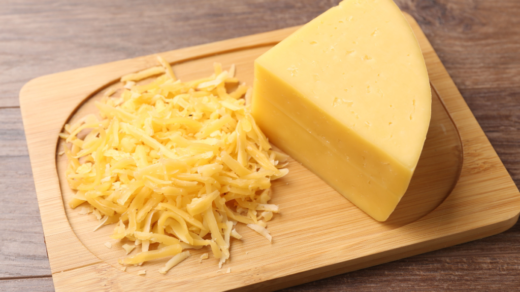 Queijo entra na dieta de quem tem diabetes? Veja o que muda com o tipo, a porção e o horário Queijo em pedaço e ralado sobre tábua de madeira
