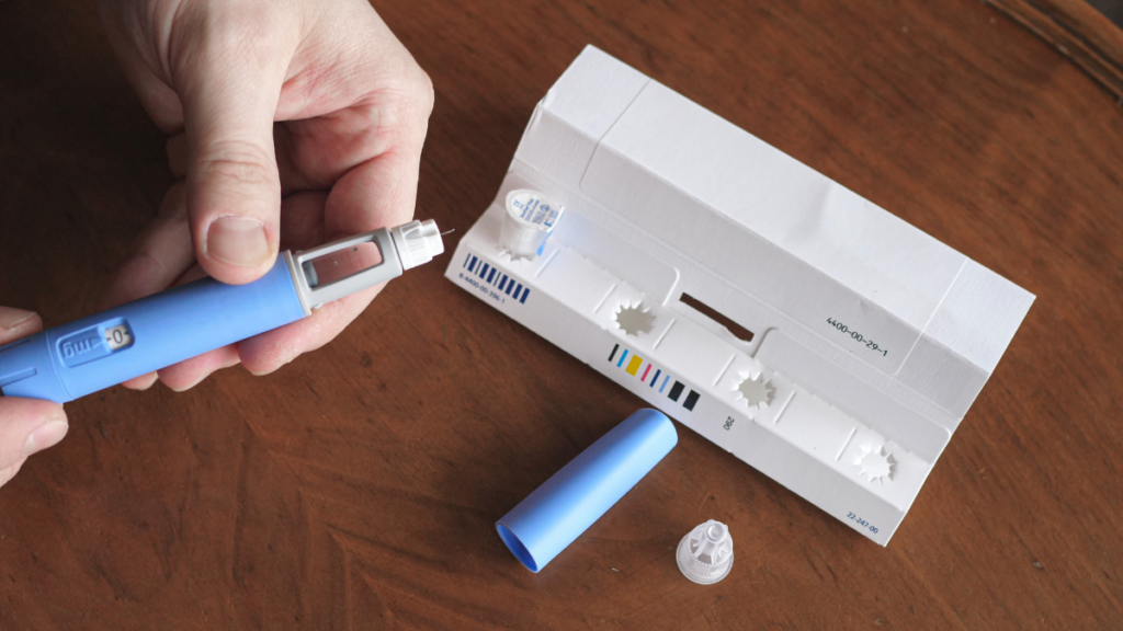 Semaglutida sintética ou genérica? Entenda o que muda para quem tem diabetes Caneta de semaglutida genérica e agulhas sobre uma mesa de madeira