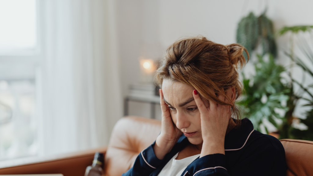 Cortisol aumenta a glicemia? Entenda o que acontece com o corpo durante o estresse Mulher sentada com as mãos na cabeça, demonstrando sinais de estresse e preocupação relacionados ao aumento do cortisol.