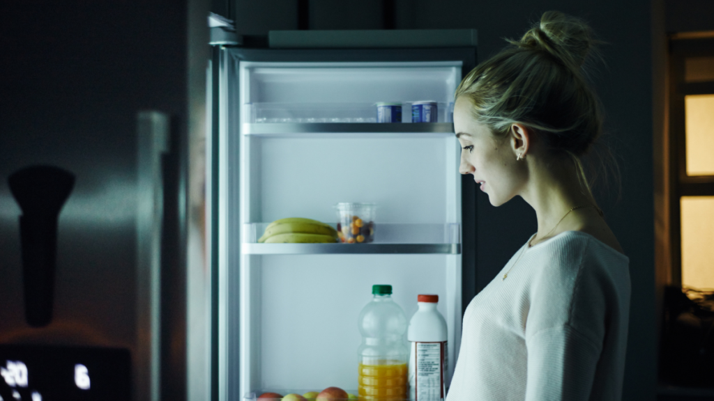 Hipoglicemia à noite no diabetes: o que comer antes de dormir para reduzir riscos sem exagerar na ceia Mulher abre a geladeira durante a noite em busca de alimento