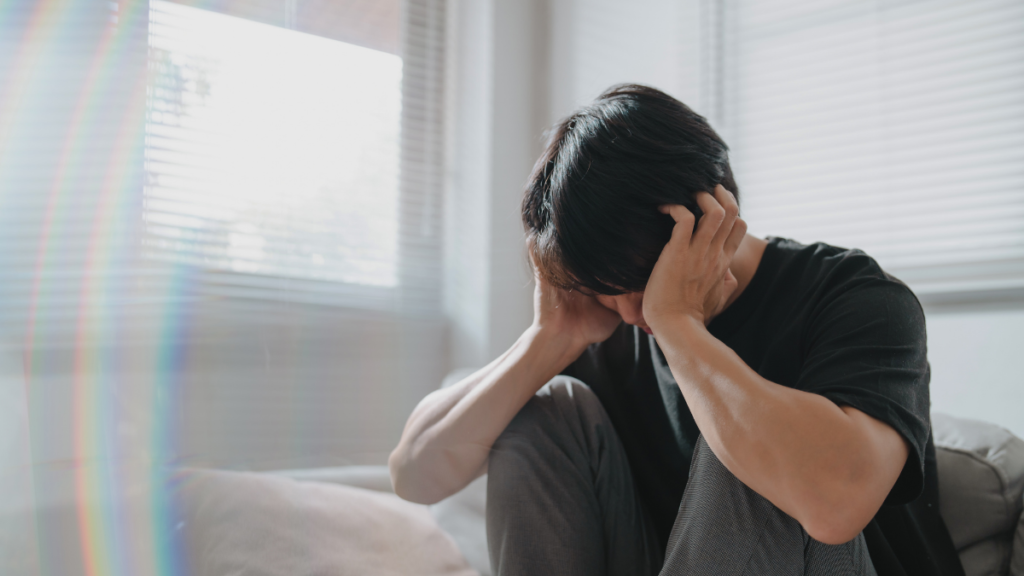 Setembro Amarelo: entenda a importância da saúde mental no controle da glicose de quem tem diabetes Homem sentado no sofá com as mãos na cabeça, demonstrando sofrimento emocional