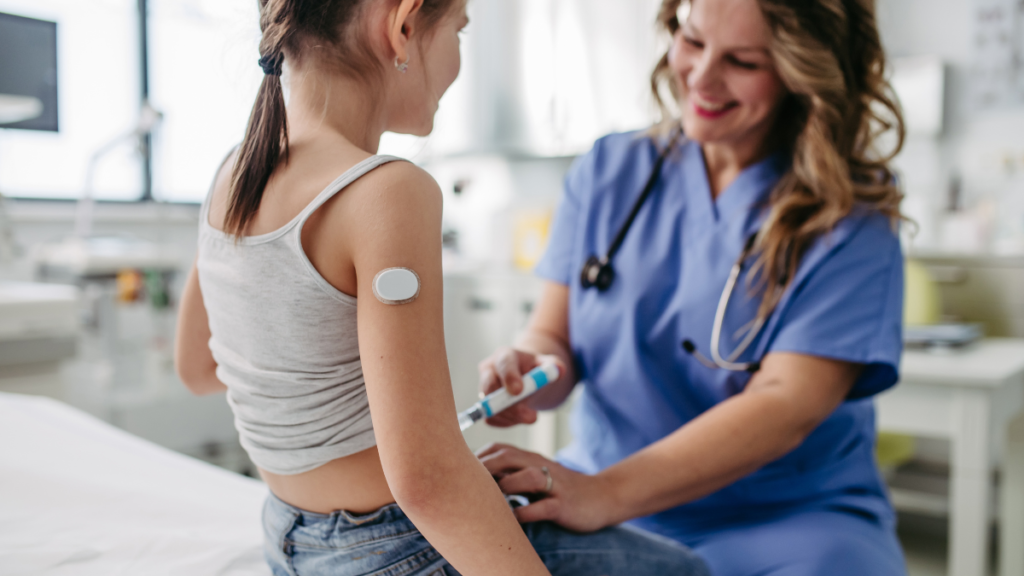 Criança com diabetes pode comer doces e ir a festas? O que a família precisa saber Criança com sensor de glicose no braço durante atendimento de saúde para diagnóstico de diabetes infantil.