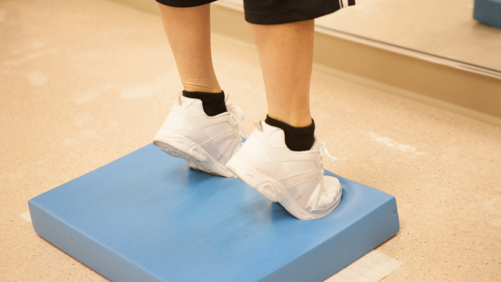 Levantar o calcanhar ajuda a baixar a glicose? Entenda Pessoa levantando os calcanhares sobre uma plataforma durante exercício físico para ajudar a baixar a glicose.